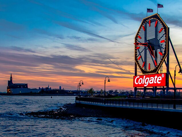 morska obala, logotip Colgatea u pozadini ispod velikog sata s crvenim kazaljkama
